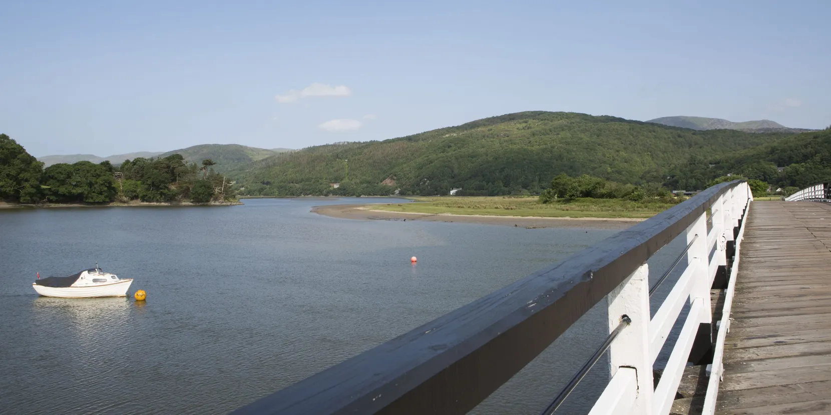 A landscape shot of mountains and water in front of it. There is also a boat in the background