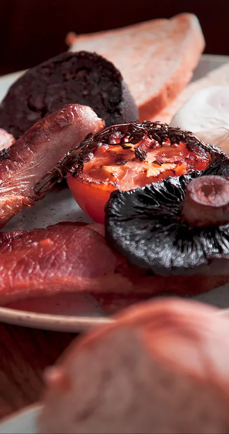Breakfast related items on a plate including toast, bacon and tomato
