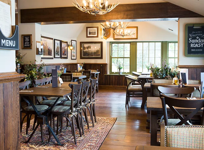 Decor in a pub. There is some pictures on the wall and several wooden tables with seats around it