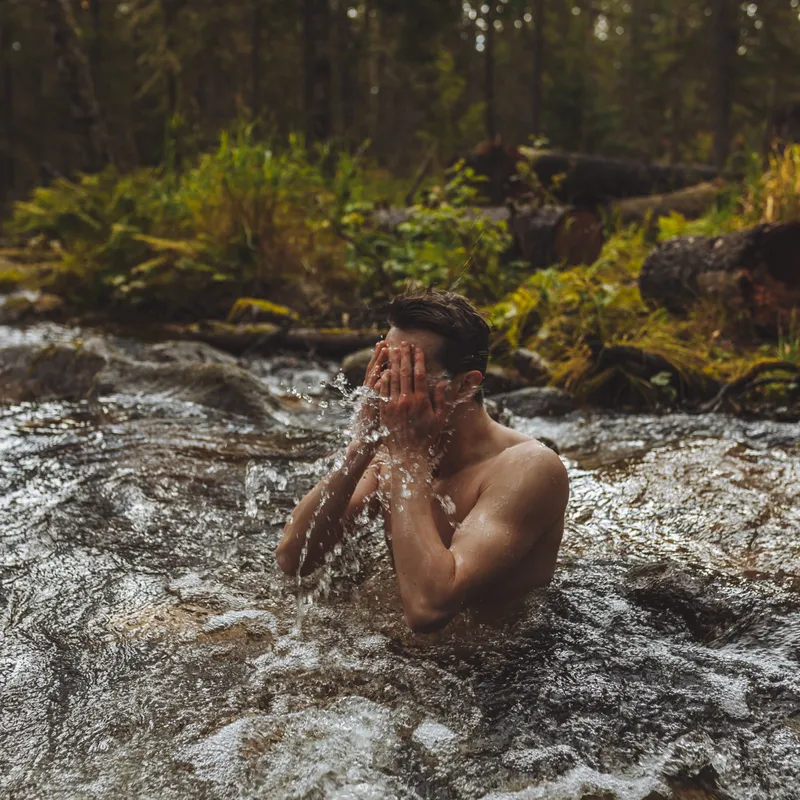 An image of a person in water. Their hands are on their face
