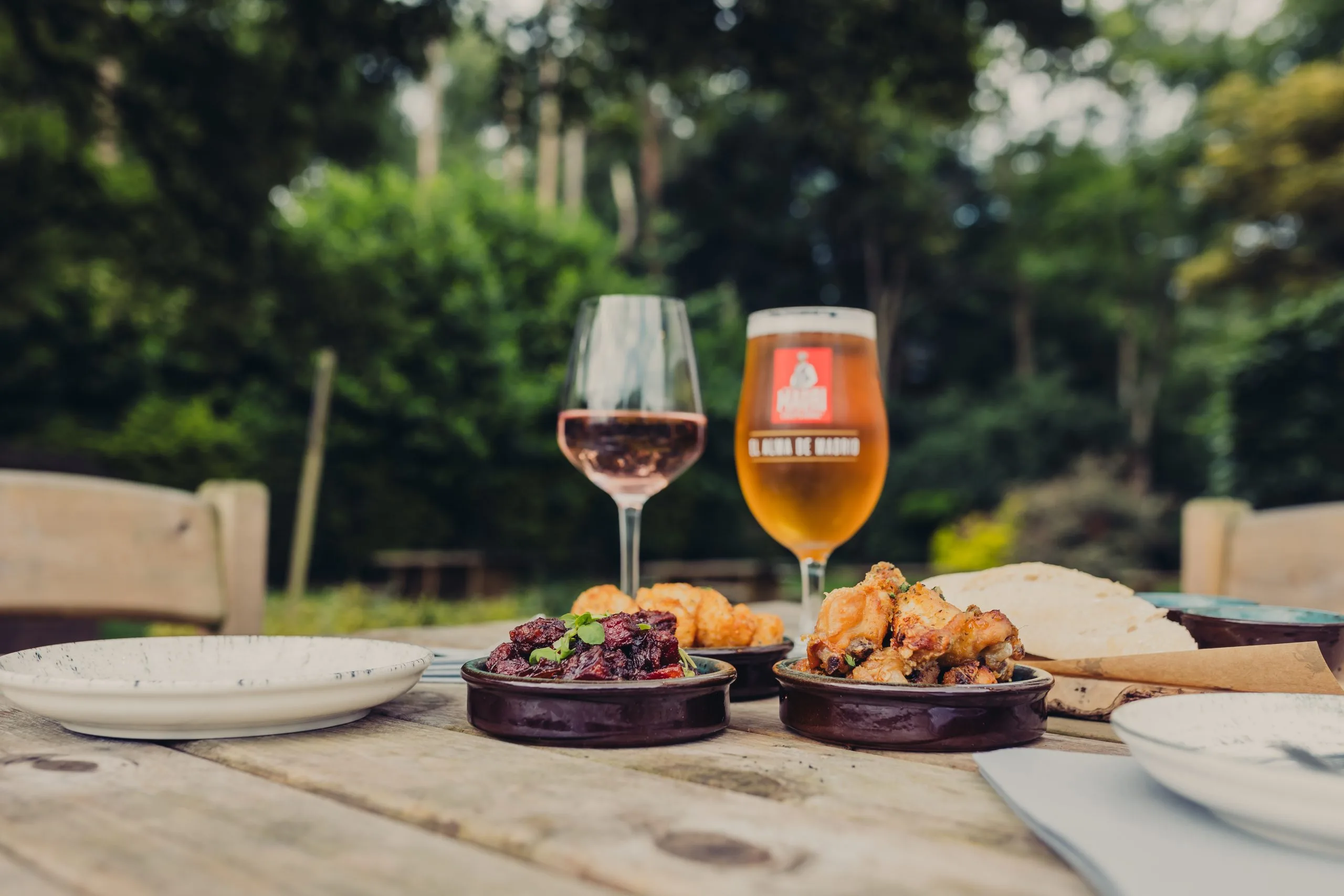 Table situated outside with several dishes and two wine glasses