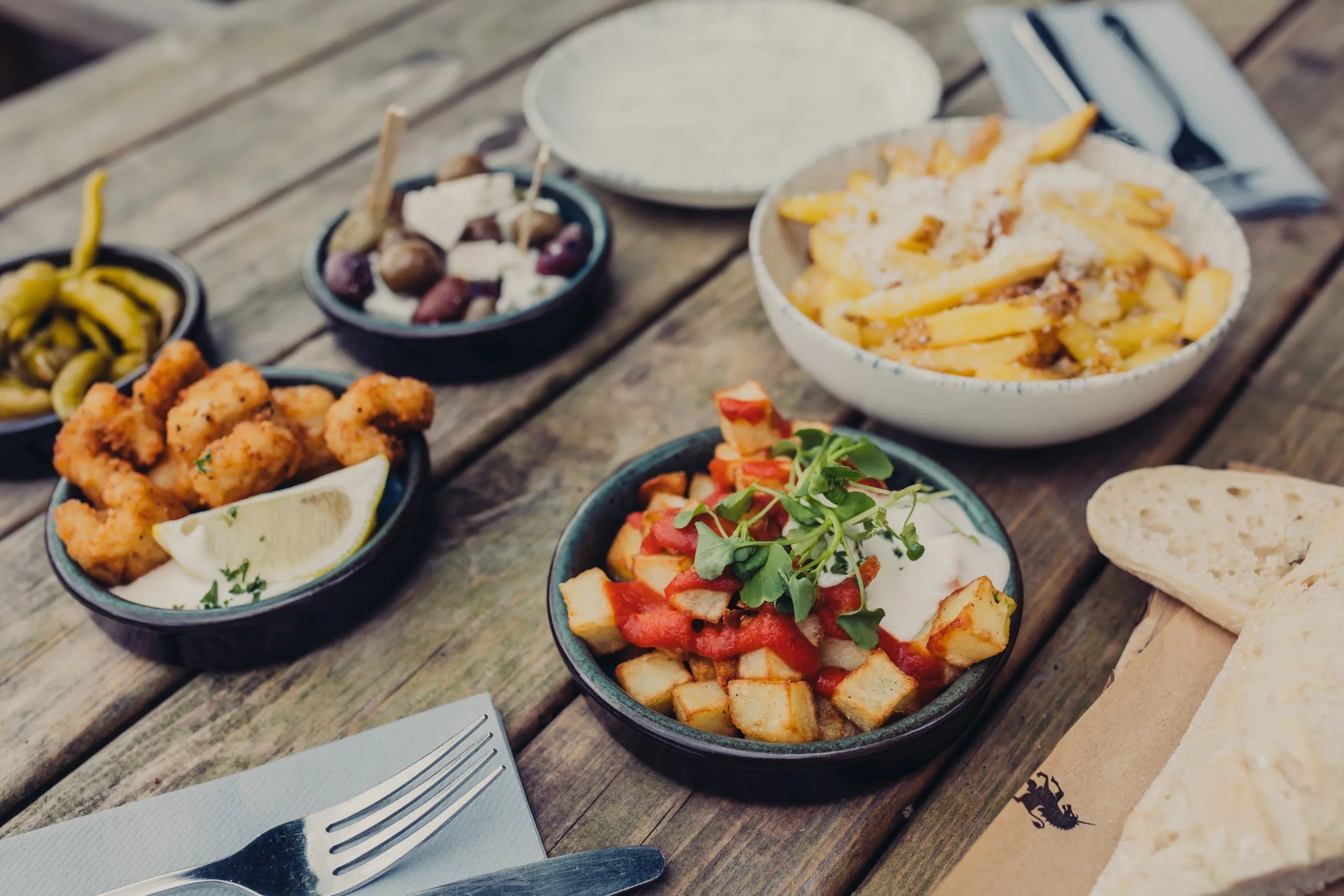 Various small dishes on a table with someone putting their fork into one