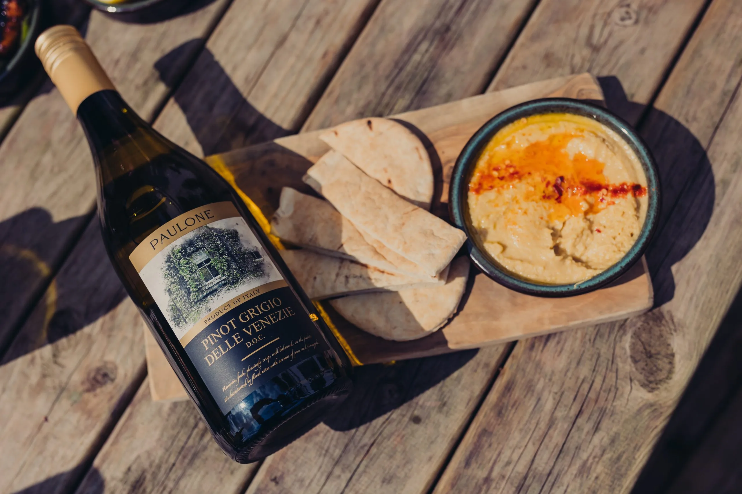 Pitta bread next to a dish. Next to the pitta bread is wine.