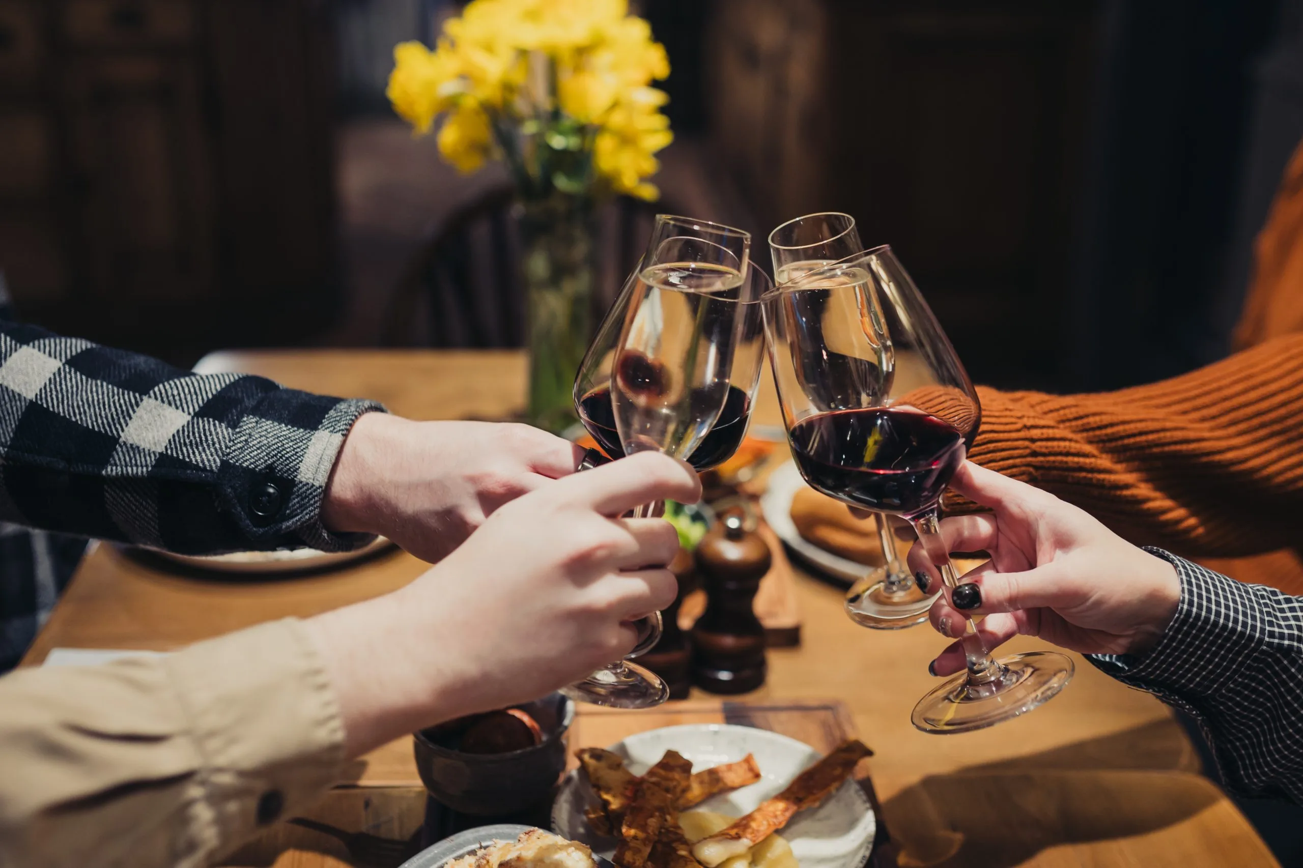 Four people clinking wine glasses