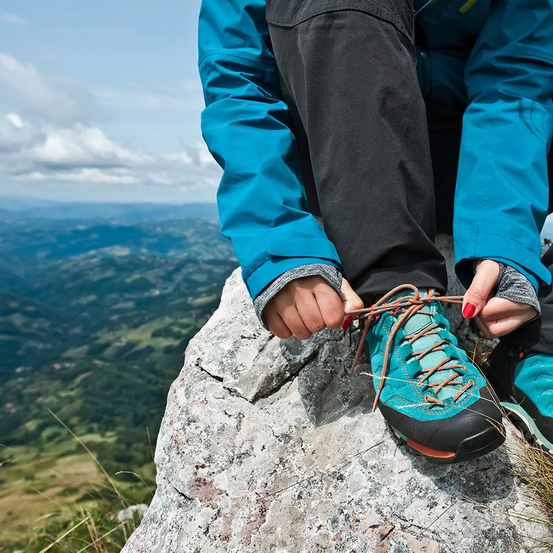 Someone tying their shoelaces on a rock.