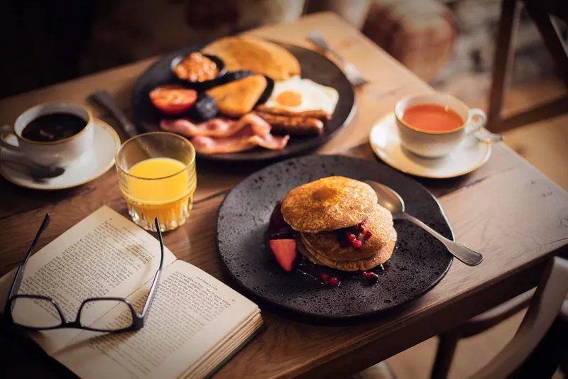 Various breakfast items including bacon, pancake, tea and coffee